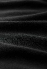 Schwarzer Stoff mit weicher Textur, der subtile Wellen und Falten zeigt. Die Oberfläche hat eine feine Webart, die ein glattes Aussehen erzeugt.