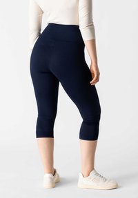 Leggings capri blu navy con vita alta, realizzati in tessuto elasticizzato, caratterizzati da una texture liscia e senza motivi o hardware visibili.