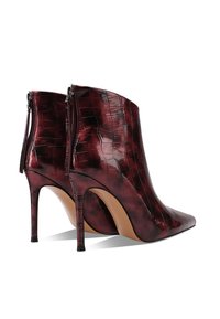 Botas de tobillo de charol burdeos con punta afilada, patrón de cocodrilo y cierre de cremallera en la parte posterior. Los tacones altos y delgados completan el diseño.