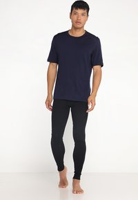 Chemise navy à manches courtes avec un col rond assortie à des leggings noirs. Les deux pièces sont ajustées, fabriquées dans un tissu extensible avec une texture lisse.