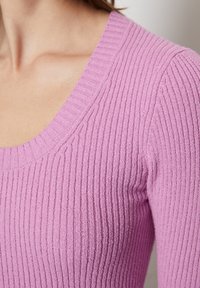 Sweater en tricot côtelé rose clair avec un large décolleté en scoop et des manches longues, mettant en valeur une texture douce et une silhouette ajustée.