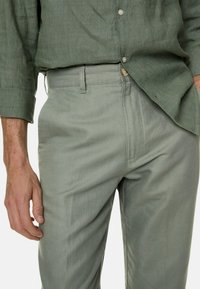 Lichtgroene linnen broek met een rechte pasvorm, voorzien van een platte voorkant, zijzakken en een subtiele textuur. Knopsluiting bij de taille.