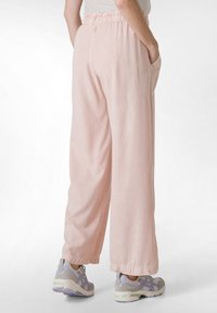 Lichtroze wijde broekspijpen van zachte stof, met een elastische tailleband en zijzakken. Gecombineerd met grijze en lavendel sneakers.