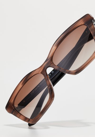 Ochelari de soare tortoise brown cu rame largi, lentile întunecate și brațe negre; prezintă branding pe brațul interior.