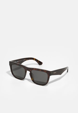 Óculos de sol em padrão tartaruga com armações quadradas e lentes escuras. Apresenta hastes grossas e uma textura suave, com um detalhe discreto da marca em uma das hastes.