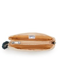 Ritstas in lichtbeige stof met afgeronde hoeken. Het interieur heeft twee compartimenten, waarvan één met een rits en een fluffy pomponaccent.