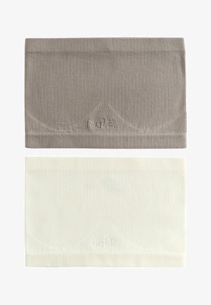 Frau mit lockigem Haar, die ein taupefarbenes, geripptes Bandeau und weiße Unterwäsche mit dem "self."-Logo trägt, richtet ein hellblau gestreiftes Hemd von den Schultern.