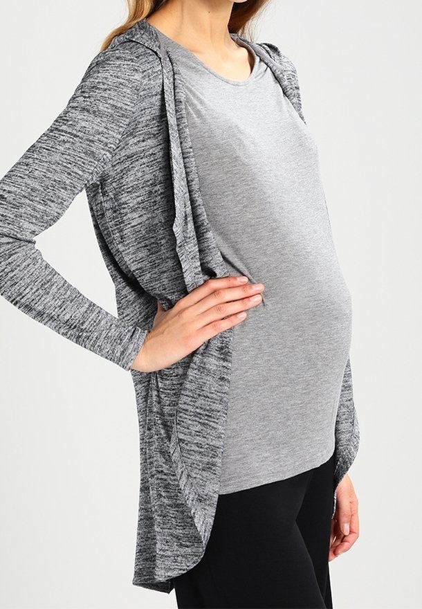 Šedý cardigan s dlouhým rukávem a kapucí, který má melírovanou texturu, vrstvený otevřený předek, nošený přes šedý top a černé kalhoty.