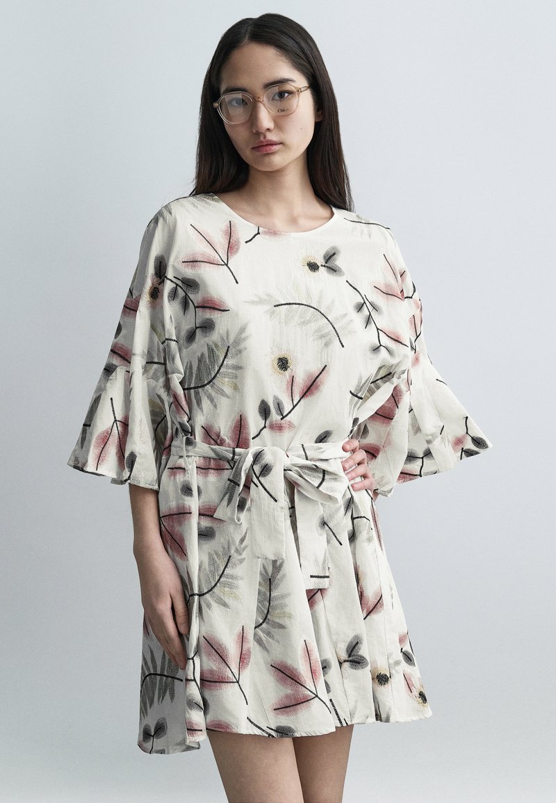 Φόρεμα με λουλουδάτο μοτίβο, κοντά μανίκια, από ελαφρύ ύφασμα, με ροζ και γκρι φύλλα. Διαθέτει ζώνη στη μέση και φαρδιά, χαλαρά μανίκια.