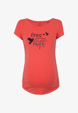 Koralowa koszulka ciążowa z czarnym tekstem "free in my faith" i trzema sylwetkami ptaków na piersi.