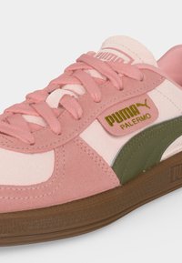 Ροζ και μπεζ αθλητικό παπούτσι Puma Palermo με ροζ κορδόνια, πράσινη ρίγα, καφέ σόλα και χρυσό λογότυπο Puma Palermo στο πλάι.