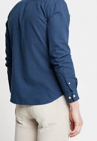 Laivastonsininen pitkähiha-paita, jossa on hienovarainen kuvio, napilliset mansetit ja pyöristetty helma. Valmistettu teksturoidusta puuvillakankaasta.