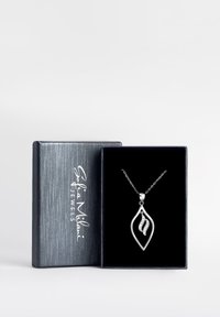 Sølvbladformet vedhæng med en kæde, der har en glat overflade og en subtil glans fra indlagte ædelsten, præsenteret i en sort fløjlæske.