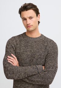Brown and cream knitted sweater with a textured pattern, crew neckline, and ribbed cuffs. Features a relaxed fit and raglan sleeves.