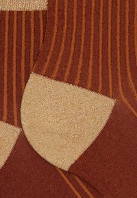 Calze marroni con luccichio dorato, caratterizzate da una trama a costine verticali e da un accento dorato contrastante nell'area delle punte. Design a maglia piatta.