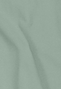 Tissu vert menthe clair avec une texture lisse et un fin côtelé, présentant des variations subtiles de teinte et de douces plis.