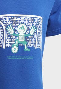 Camiseta de algodón azul con un personaje de dibujos animados verde sosteniendo un balón de fútbol, diseño gráfico de una portería y el texto "ADIDAS 03".