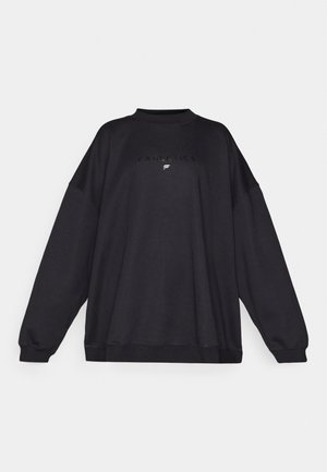 Čierna oversized mikina vyrobená z mäkkej tkaniny, s vysokým golierom a ribbovanými manžetami. Na prednej strane je vyrazené logo "Fabletics."