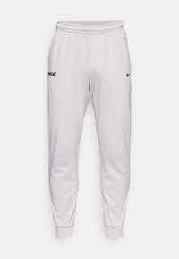 Svetločervené Nike tepláky s elastickým pásom, zúženými nohavicami, bočnými vreckami a potlačeným logom na ľavom stehne. Mäkký, hladký povrch.