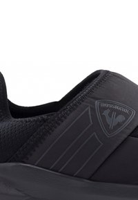 Scarpa sportiva nera con tomaia in mesh testurizzato, accenti lisci, patch con logo e colletto elastico per una facile calzata. Suola rinforzata.