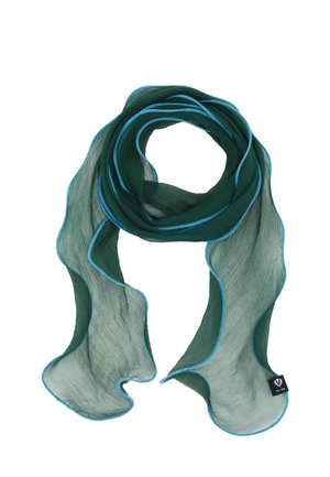 Woman with long blonde hair wearing a light purple ribbed sweater and blue jeans, accessorized with a long dark green scarf.