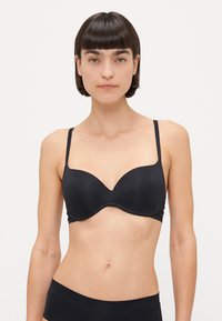 Reggiseno nero con ferretto, coppe lisce e modellate, spalline regolabili e lati senza cuciture. Il materiale ha una finitura opaca.