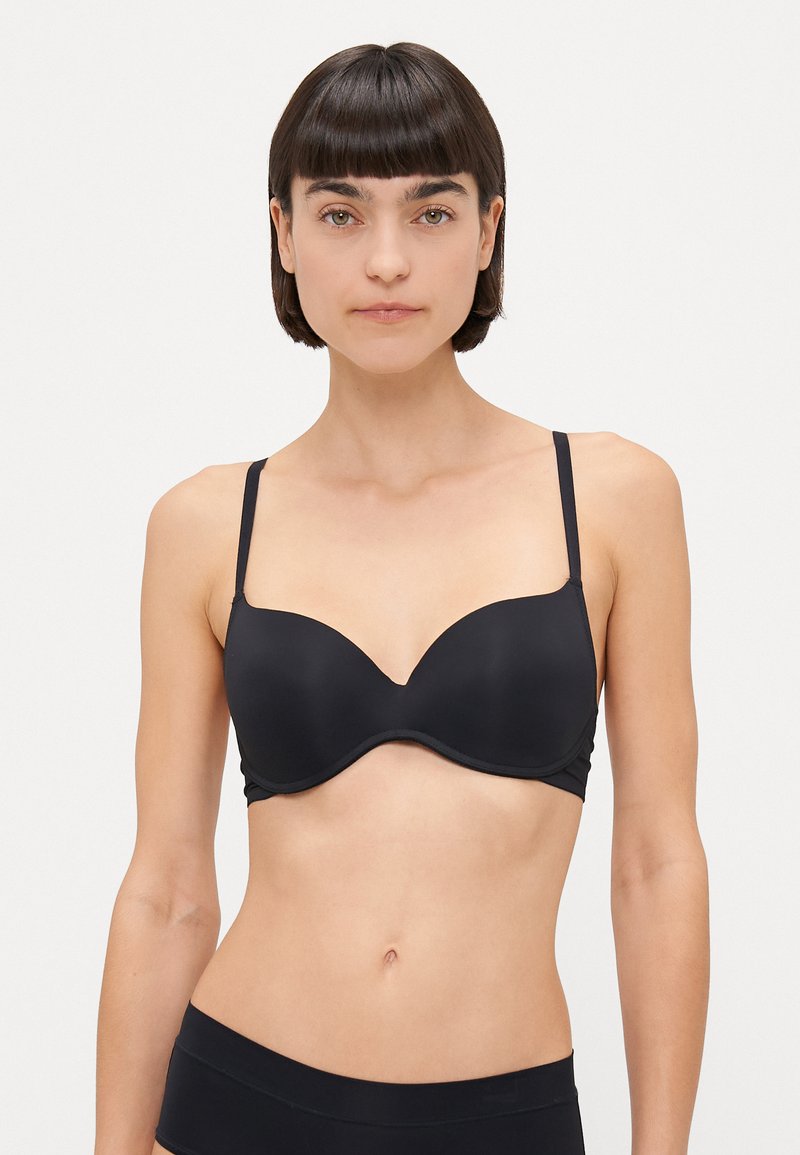 Reggiseno nero con ferretto, coppe lisce e modellate, spalline regolabili e lati senza cuciture. Il materiale ha una finitura opaca.