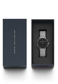 Montre Daniel Wellington à cadran noir avec bracelet en maille argentée dans un étui en mousse noire à côté d'une élégante boîte bleu foncé avec lettrage doré.