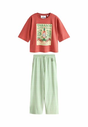 Rød kort T-shirt med vintage Tabasco-flasketryk og lysegrønne og hvide lodrette stribede løse bukser med elastisk talje.