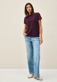 Kortärmad, texturerad topp i burgundy som är kombinerad med ljusblå vida jeans och vita sneakers. Enkel, avslappnad passform; inga synliga logotyper.