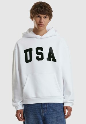 White hooded sweatshirt with black "USA" lettering, front pocket, soft texture, loose fit, ribbed cuffs, and waistband.