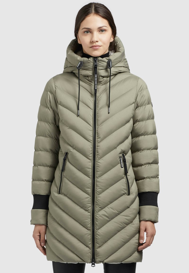 Puffa-jacka i olivgrön med chevron-quilting, hög huva, framsida med blixtlås och två sidfickor med svarta blixtlåsdetaljer.