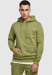 Sudadera con capucha en color verde oliva, fabricada con un tejido suave; cuenta con un bolsillo delantero, capucha con cordón y puños y dobladillo de canalé.