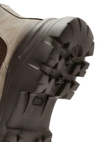 Bottine en cuir marron avec une surface texturée, dotée d'une robuste semelle en caoutchouc avec des profondes rainures pour une traction et une stabilité optimales.