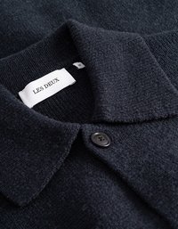 Tumšs jūras zila džemperis ar rakstainu adījumu, ar izkliedētu apkakli un vienu melnu pogu pie atlas. Uz etiķetes ir rakstīts "LES DEUX", izmērs M.