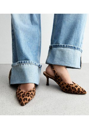 Leoprint Slingback-Absatzschuhe mit spitz zulaufender Zehenpartie und einem kleinen Stilettoabsatz, kombiniert mit hellblauen weit geschnittenen Jeans mit ausgefransten Säumen.