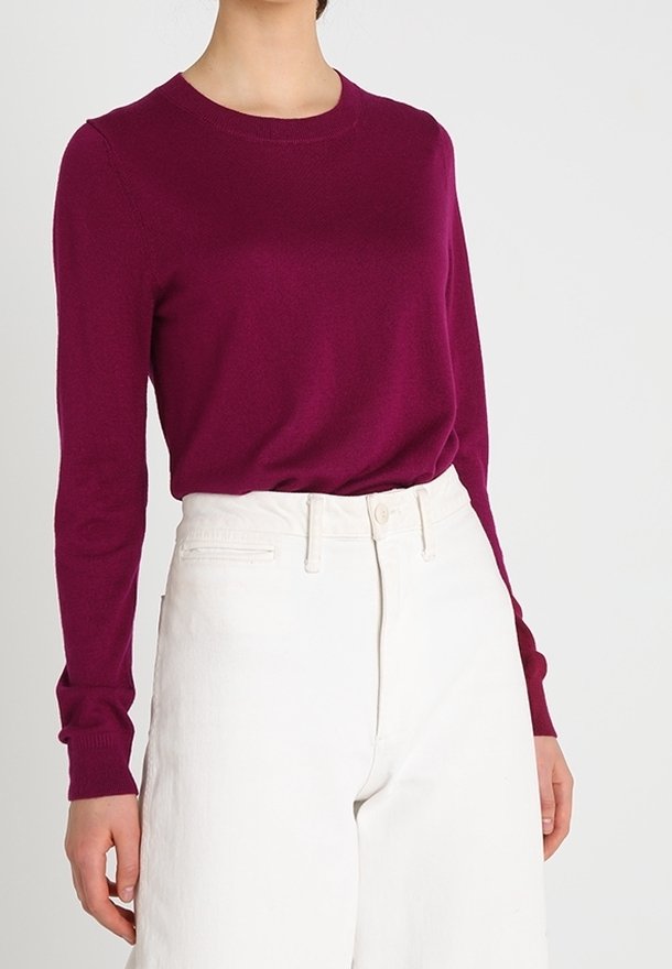 Magenta långärmad tröja med rund halsringning, tillverkad av mjukt stickat tyg. Matchas med vit högmidjad vida byxor.