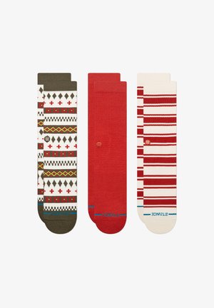 Tres pares de calcetines: uno con un patrón geométrico en crema, verde y rojo; uno rojo liso; y otro con rayas rojas sobre crema. Material de punto suave.