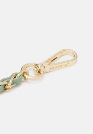Fermoir en métal ton doré avec gravure Valentino attaché à une sangle en cuir vert et chaîne sur fond blanc.
