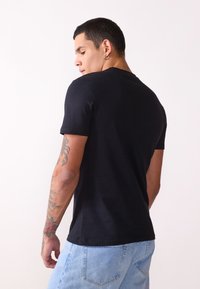 Zwart korte mouwen t-shirt van katoen, met een ronde halslijn en een aansluitende pasvorm, met textuuraccenten zichtbaar op de mouwen.