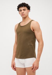 Débardeur vert olive avec un col rond et des bords côtelés, fabriqué en mélange de coton doux, présentant un logo discret près de l'ourlet.