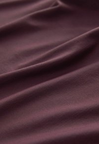 Burgundia veniv kangas pehme tekstuuriga, mis sisaldab siledaid, voolavaid kortse ja kerget välimust.