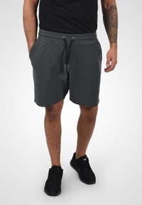 Gray cotton shorts with elastic waistband, adjustable drawstring, and side pockets. Worn with black sports shoes.