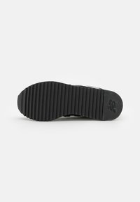 Black rubber shoe sole with horizontal grooves, featuring a rounded toe and a logo embossed near the heel. Textured surface for grip.