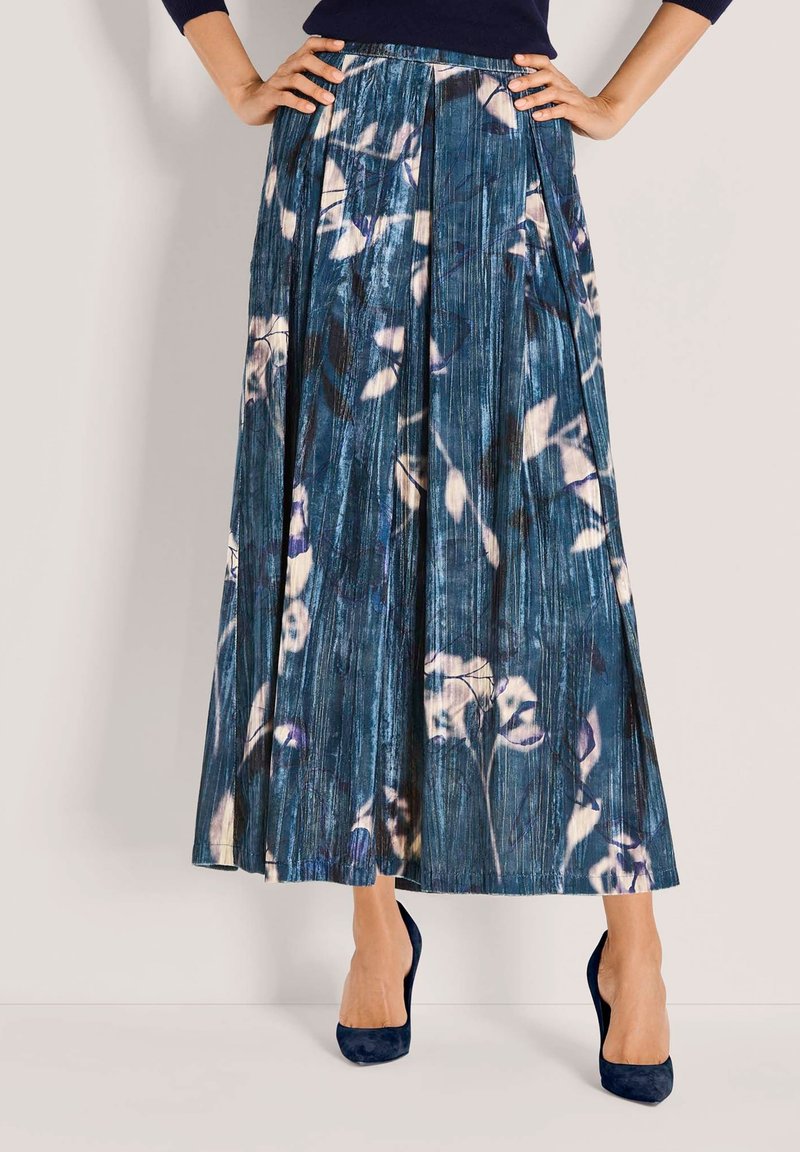 Pliseerrokken met een bloemenpatroon in blauwe, witte en paarse tinten. Gemaakt van gestructureerde stof, gecombineerd met marineblauwe hakken.
