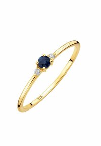Bague en or avec une finition polie, dotée d'une pierre centrale ronde en saphir bleu et de deux petites pierres blanches en accent de chaque côté.