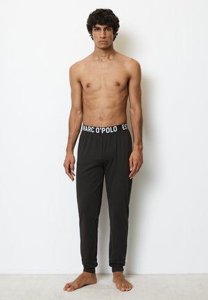 Zwarte sweatpants met elastische tailleband en witte "MARC O'POLO" branding. Gemaakt van een gladde stof, taps toelopend bij de enkel.