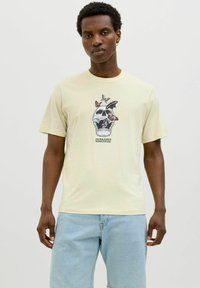 Geel katoenen T-shirt met een schedelafbeelding vergezeld van vlinders en de tekst "JACK & JONES WORLDWIDE", korte mouwen en een ronde hals.
