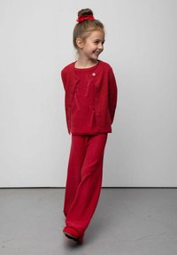 Czerwony zestaw z dzianiny składający się z swetra i spodni z fakturowanym kardiganem, dopasowanym topem i spodniami o szerokich nogawkach. Charakterystyczny detal z guzikami na kardiganie.