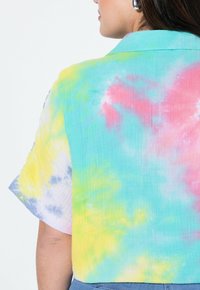 Maglietta corta a maniche corte con motivo tie-dye in colori pastello: blu, giallo, rosa e verde. Tessuto morbido e leggero.